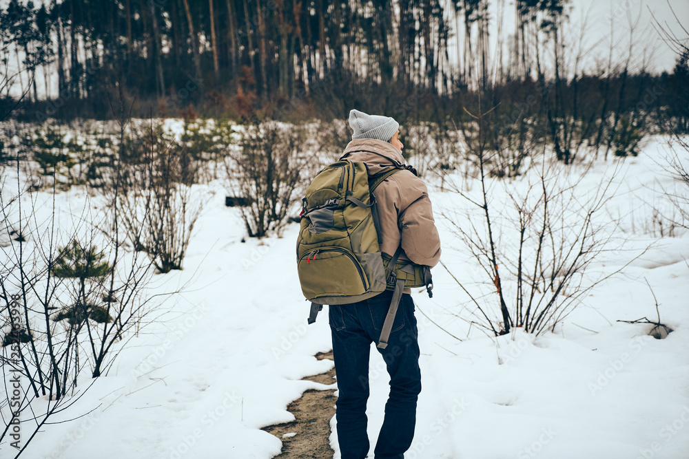Naklejka premium Senior man wearing stylish winter clothes and backpack traveling in a forest