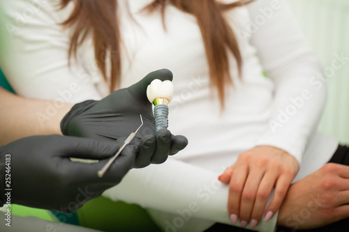 Dentist explaining teeth model to female patient. Technical shots on a dental prothetic laboratory photo