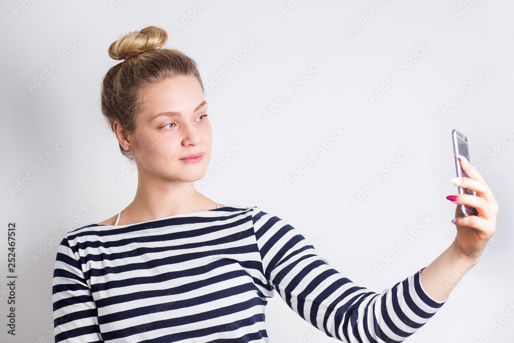 Studio portrait of beautiful blonde woman smiling with white teeth and making selfie, photographing herself over white Studio portrait of beautiful blonde woman smiling with white teeth and making selfie, photographing herself over white
