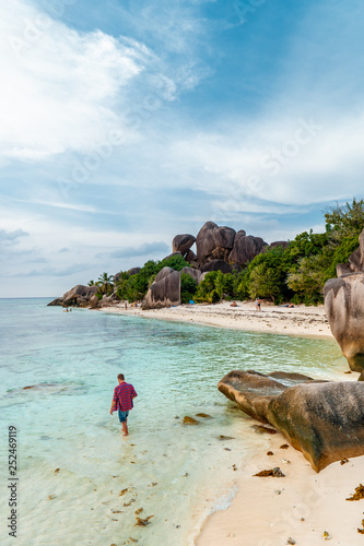 young men on tropical beach with palm tree, white beach man walking Seychelles Island, tanning men on tropical vacation photo