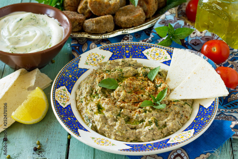 Arabic cuisine. Fresh homemade creamy mung hummus with spicy, falafel, sour cream sauce on a wooden kitchen table. Ramadan food. Arabic cuisine. Fresh homemade creamy mung hummus with spicy, falafel, sour cream sauce on a wooden kitchen table. Ramadan food.