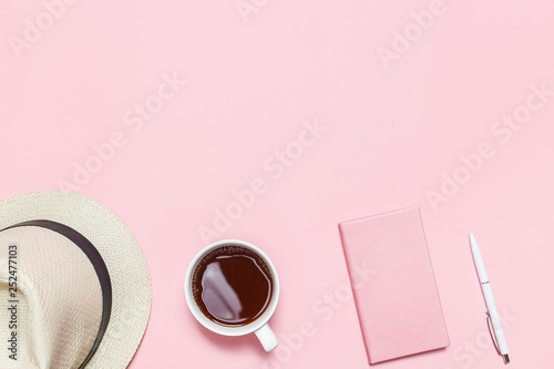 Trendy Pink table with summer hat, cup of coffee, pink notebook and pen. Top view. Flat lay template with copy space.