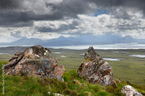 Lichen encrusted rocks overlooking the Inner Sound to Scalpay Island and the Cuillin Hills mountains Isle of Skye Scottish Highlands Scotland