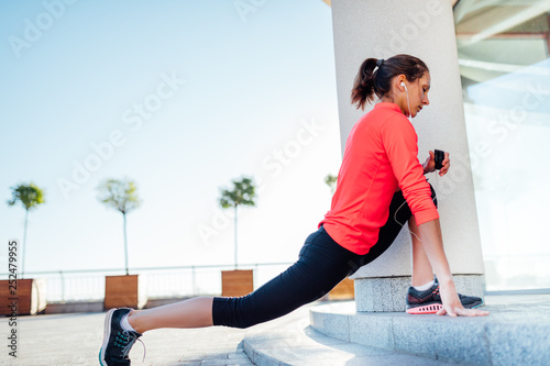 Young woman listening music while stretching before jogging exercise