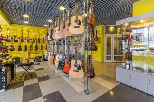Rows of guitars, both acoustic and electric in a modern musical shop.