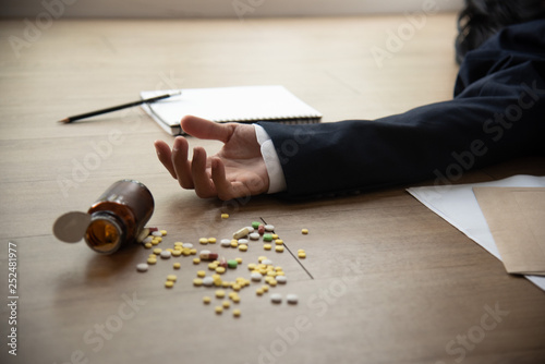Close-up hand of stressed business man suicide by taking overdose on wood ground