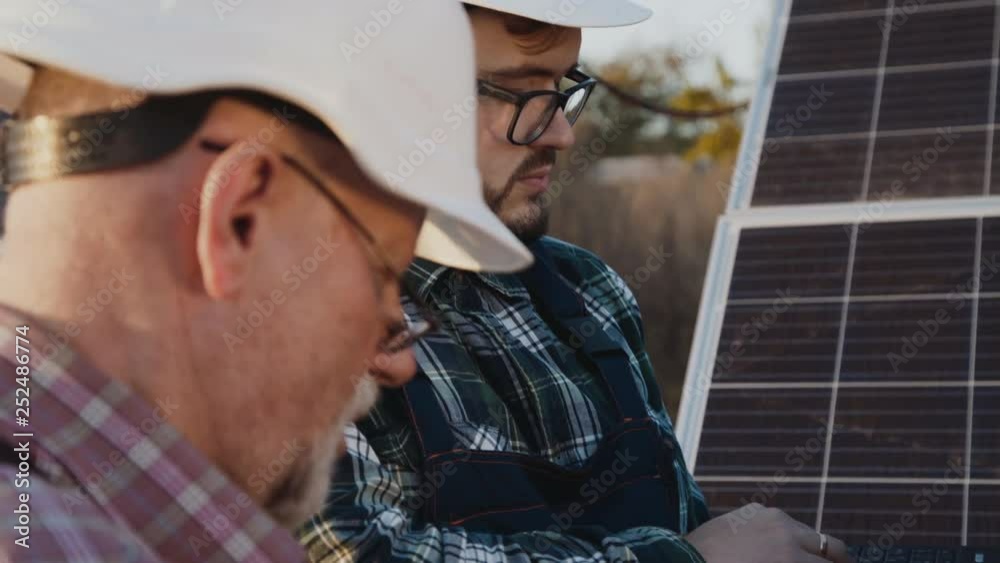 Two factory engineers noting data of work of solar batteries Two factory engineers noting data of work of solar batteries