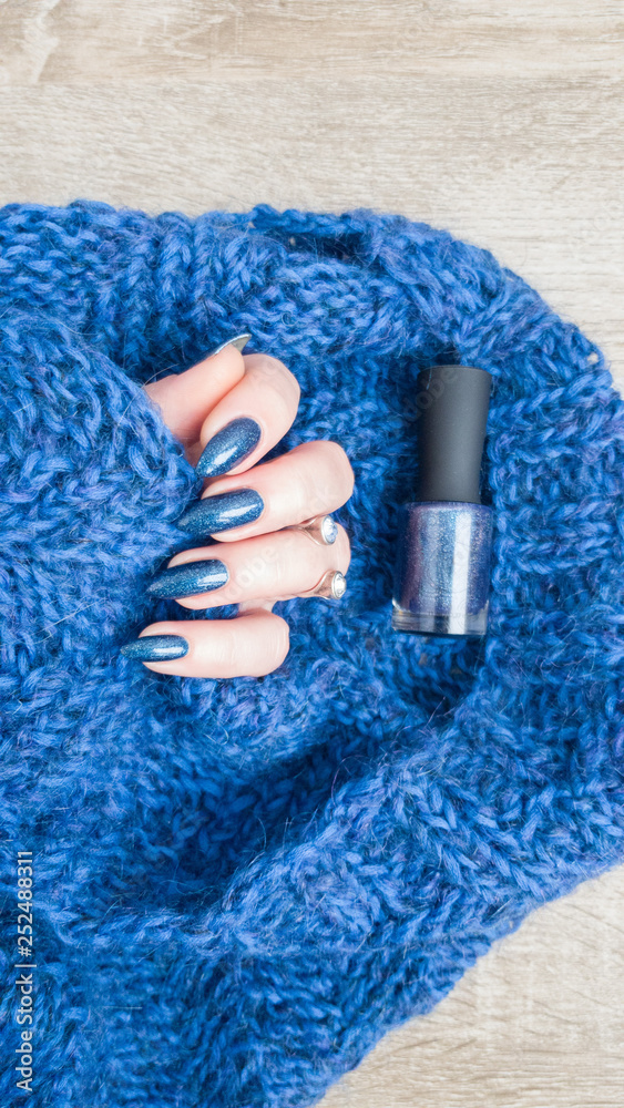 Fototapeta Female hands with long nails with blue nail polish and a bottle