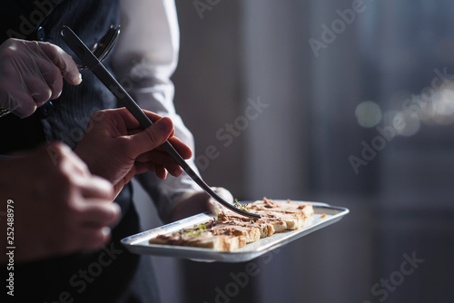 A waiter with a tray of snacks at a banquet or reception. Catering buffet at party photo