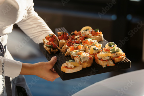 A waiter with a tray of snacks at a banquet or reception. Catering buffet at party photo