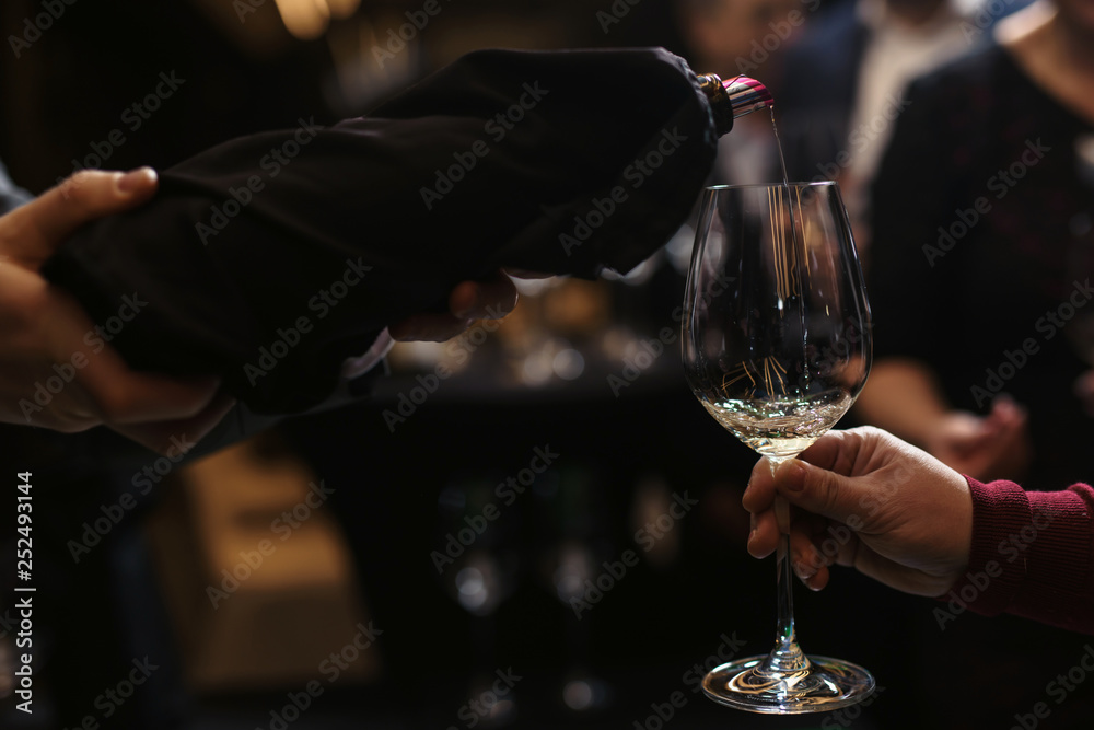 Waiter pouring wine to the glass. Woman's hand pouring wine to the glass onthe table
