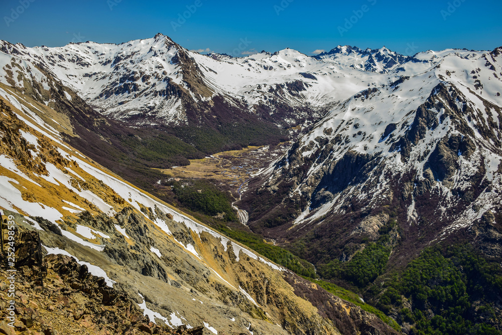 se ve las nacientes de un río que corre por un valle entre las montañas nevadas se ve las nacientes de un río que corre por un valle entre las montañas nevadas