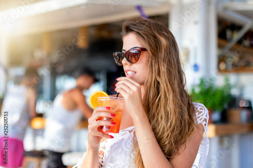Attraktive, blonde Frau im Sommer Urlaub genießt einen Cocktail an einer Strandbar