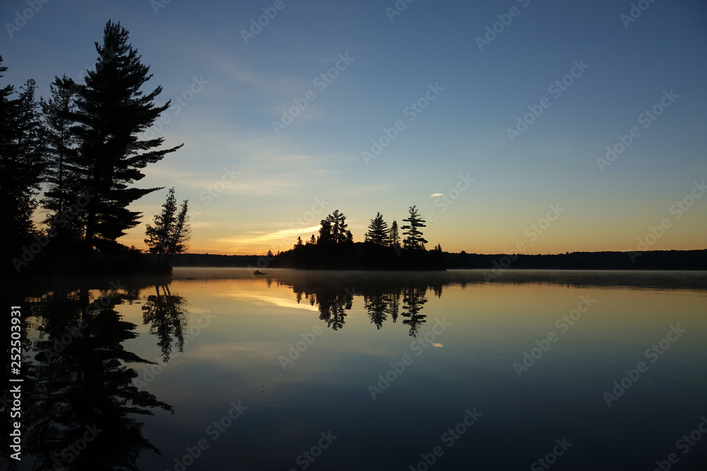Fototapeta premium sunset on lake with silhouette of trees