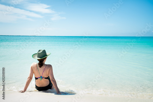 Woman with a sun hat sitting on the beach. La Tortuga Island, Venezuela