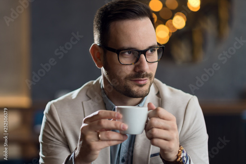 Thoughtful mid adult man drinking coffee in a cafe and looking away