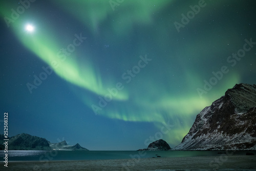 Impressive strong northern light display over Haukland beach (Lofoten, Norway) photo