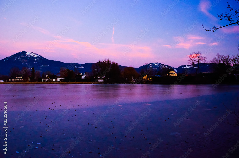 Romantic peaceful view of sunset with high mountain background in the frozen water