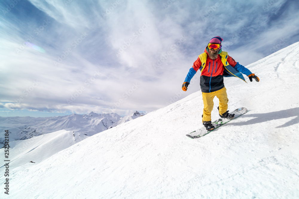 Active man snowboarder riding on slope during beautiful sunny day in the ountains.