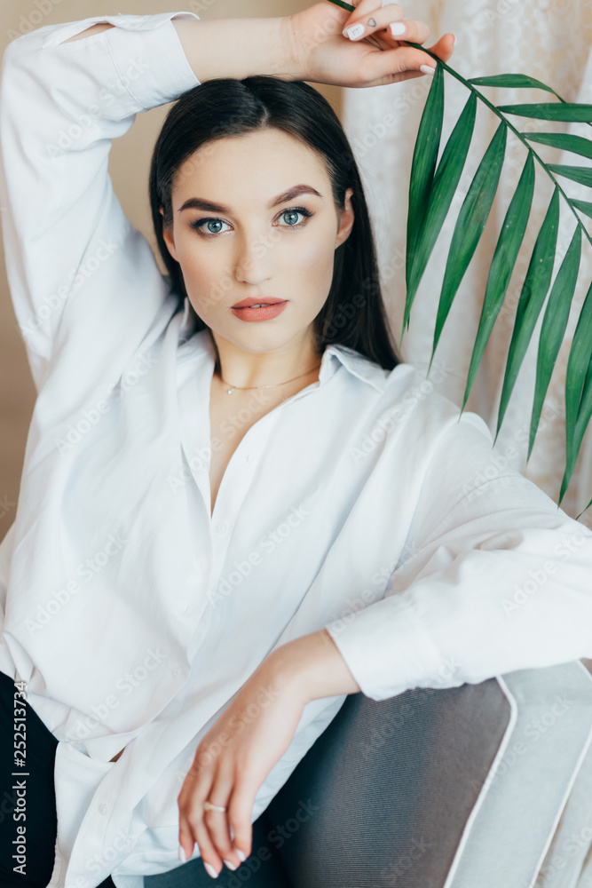 young beautiful brunette girl posing in the studio, dressed in black pants, blouse. piercing gaze young beautiful brunette girl posing in the studio, dressed in black pants, blouse. piercing gaze