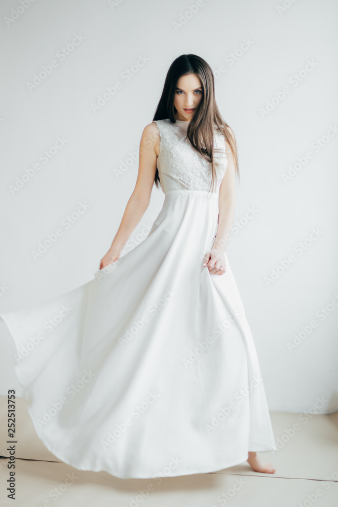 beautiful tender young girl, with flowers, dressed in a light dress, in a studio with natural light. posing, smiling, piercing gaze beautiful tender young girl, with flowers, dressed in a light dress, in a studio with natural light. posing, smiling, piercing gaze