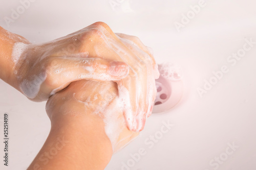 Teenager washes her hands with soap in the sink in the bathroom.