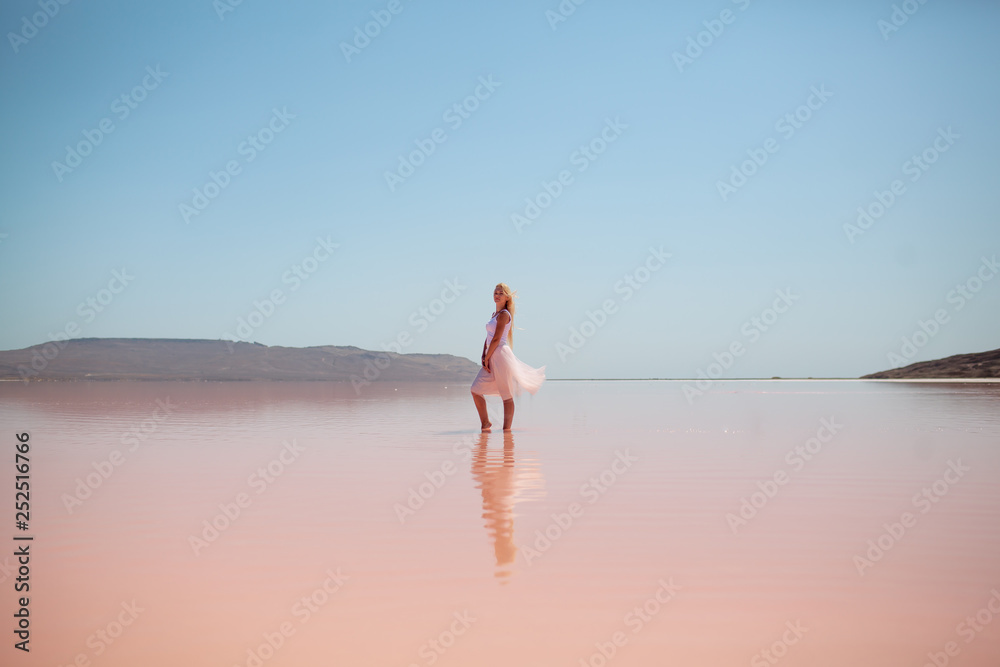 beautiful girl with long blond hair on a pink lake
