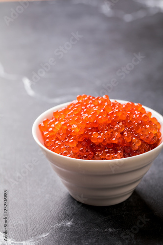 Salmon  Red Caviar in a white plate on a dark background. Healthy Food Concept. Snack.Copy space for Text.Seafood.