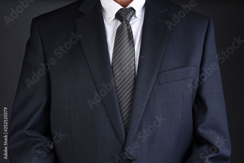 Fotografi Closeup of a man in a gray business suit with his arms at his side