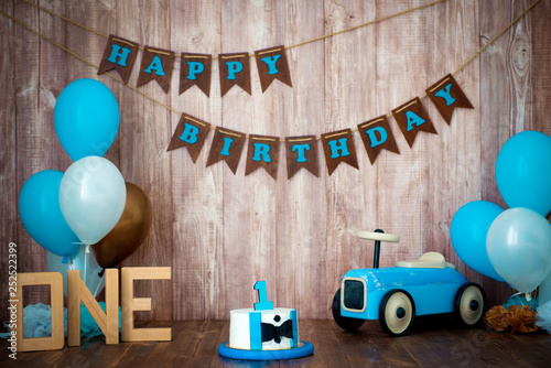 Photoshoot crush smashcake for a little boy gentleman. Decorated photozone with a wooden retro car and helium balloons. Happy birthday, 1 year photo