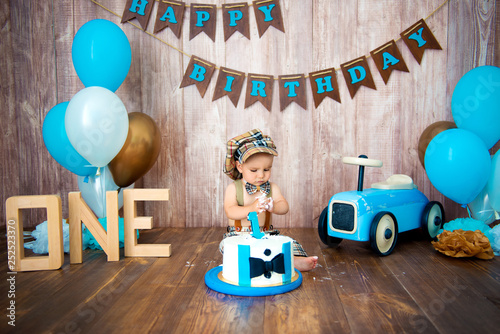 Photoshoot crush smashcake for a little boy gentleman. Decorated photozone with a wooden retro car and helium balloons. Happy birthday, 1 year photo