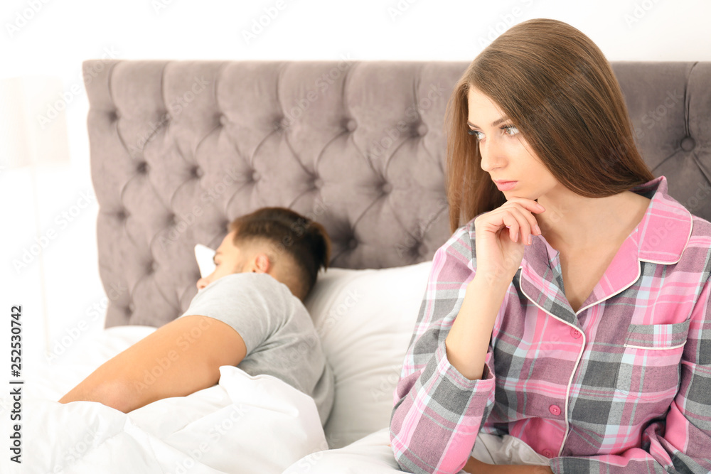 Young couple with relationship problems ignoring each other in bedroom Young couple with relationship problems ignoring each other in bedroom