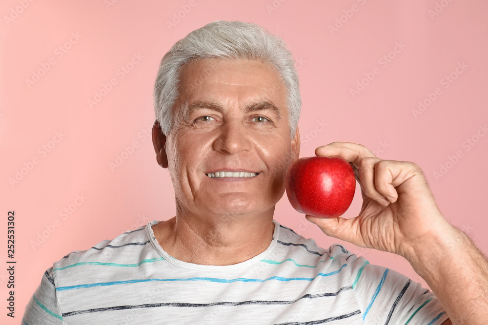 Mature man with healthy teeth and apple on color background Mature man with healthy teeth and apple on color background