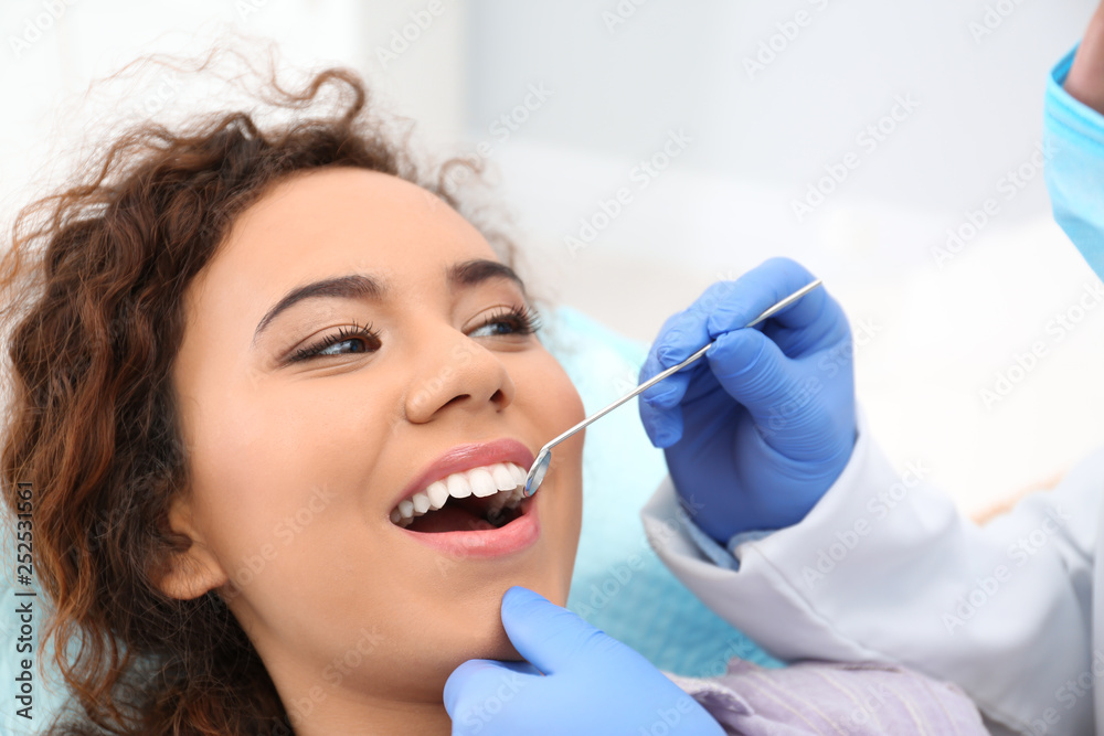 Dentist examining African-American woman's teeth in hospital
