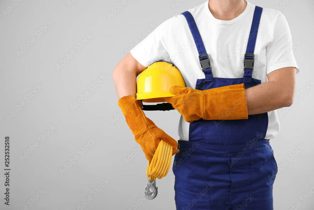 Male industrial worker in uniform on light background, closeup with space for text. Safety equipment