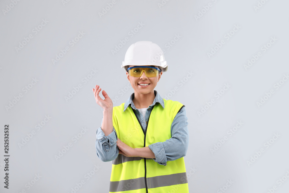 Female industrial engineer in uniform on light background. Safety equipment