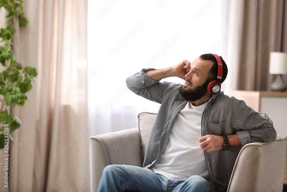 Mature man with headphones resting in armchair at home