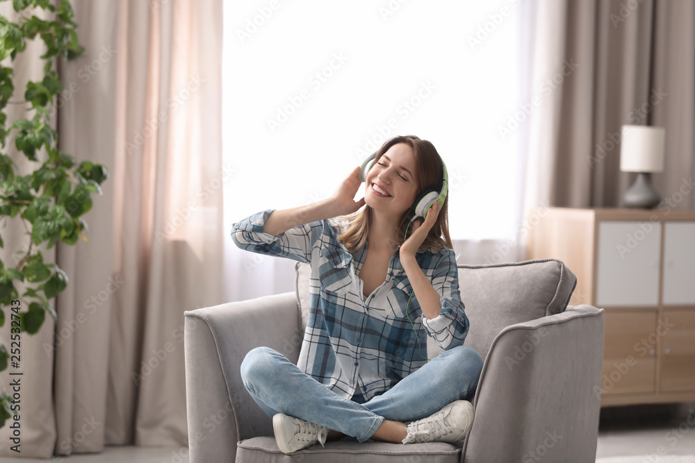 Young woman with headphones resting in armchair at home Young woman with headphones resting in armchair at home