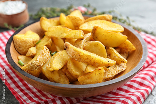 Plate with tasty baked potato wedges on table