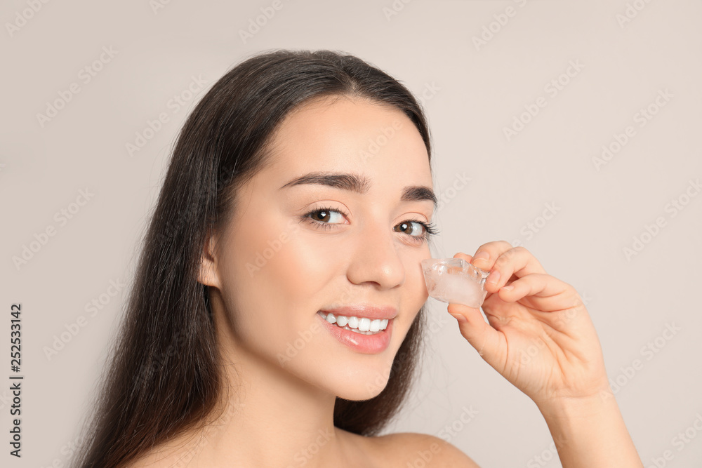 Young woman with ice cube on light background. Skin care Young woman with ice cube on light background. Skin care