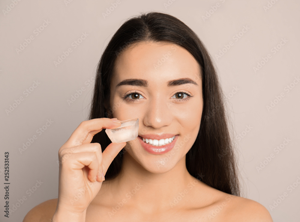 Young woman with ice cube on light background. Skin care Young woman with ice cube on light background. Skin care