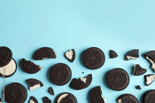 Tasty chocolate cookies with cream on color background, flat lay. Space for text photo