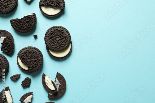 Tasty chocolate cookies with cream on color background, flat lay. Space for text photo