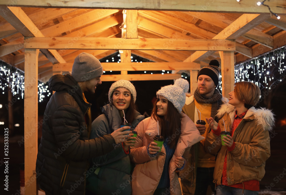 Happy friends with cups of mulled wine at winter fair Happy friends with cups of mulled wine at winter fair