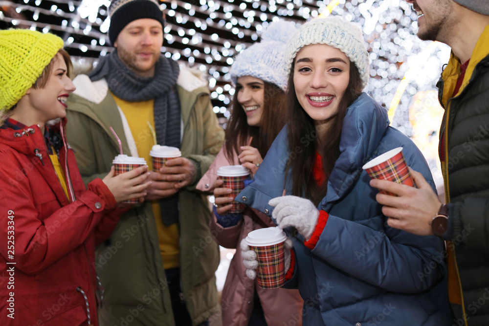 Obraz premium Happy friends with cups of mulled wine at winter fair