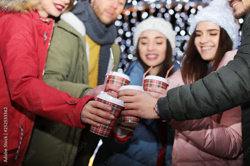 Happy friends with cups of mulled wine at winter fair Happy friends with cups of mulled wine at winter fair