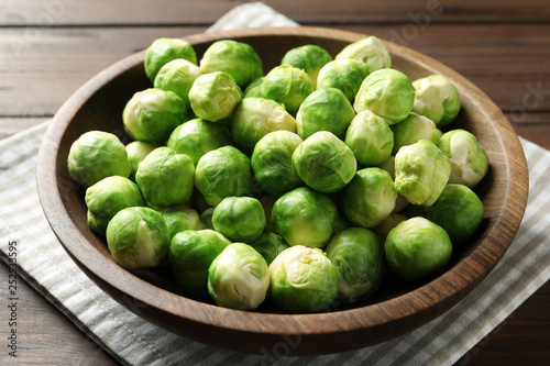 Bowl of fresh Brussels sprouts and napkin on wooden table