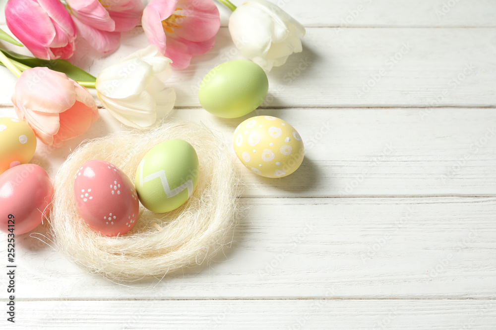 Composition with painted Easter eggs and flowers on wooden background, above view. Space for text Composition with painted Easter eggs and flowers on wooden background, above view. Space for text
