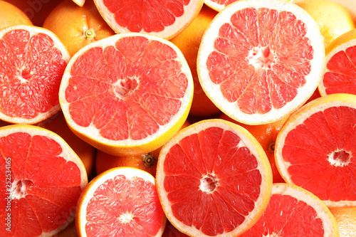 Many sliced fresh grapefruits as background  top view