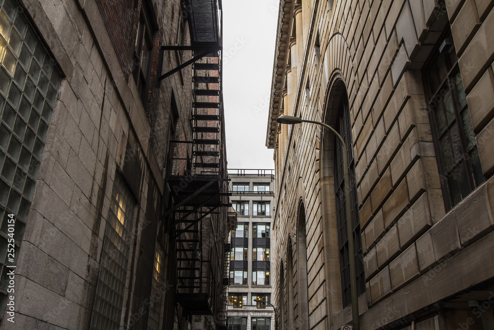 Obraz premium Fire escape stairs and ladder, in metal, on a typical North American old brick building from the Old Montreal, Quebec, Canada. These stairs, made for emergency, are symbolic of the architecture